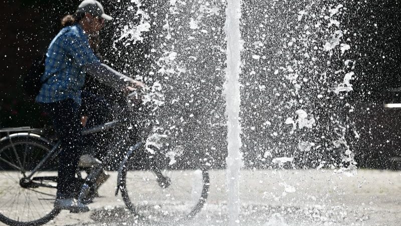 Ein Radfahrer fährt an einem Brunnen vorbei (Archivbild): In Hessen sollen die Thermometer heute auf bis zu 40 Grad klettern.