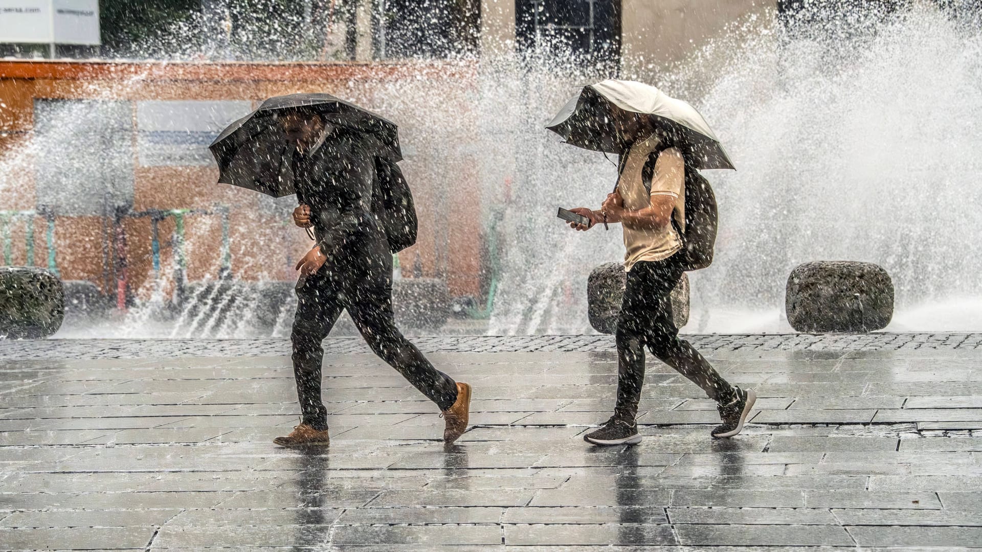 Zwei Männer flüchten vor Gewitter und Wolkenbruch am Stachus (Archivbild): Der Freitag in München wird ungemütlich.