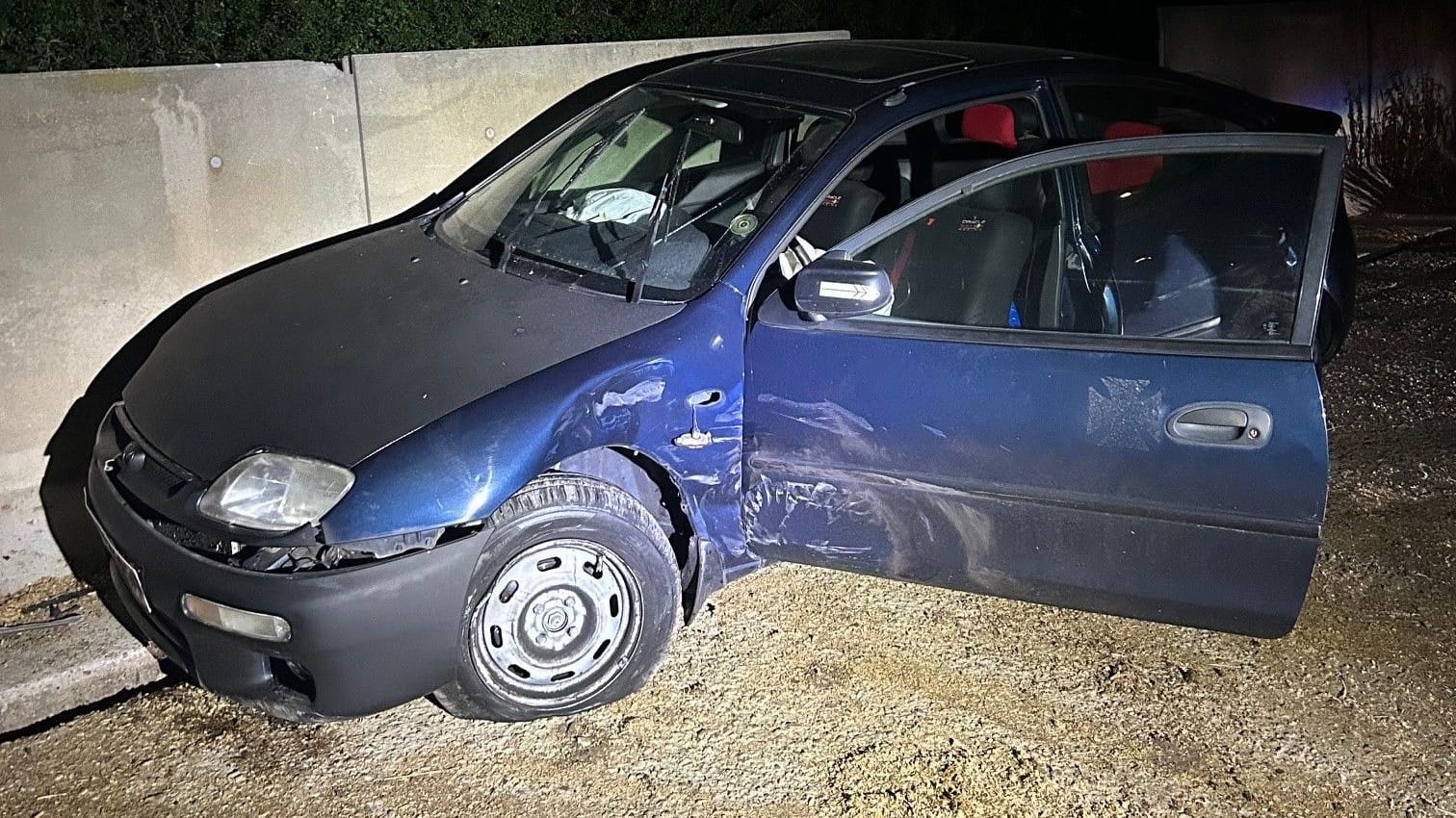 Blauer Kleinwagen steht beschädigt an einer Betonmauer: So sah das Ende einer riskanten Verfolgungsjagd durch NRW aus.