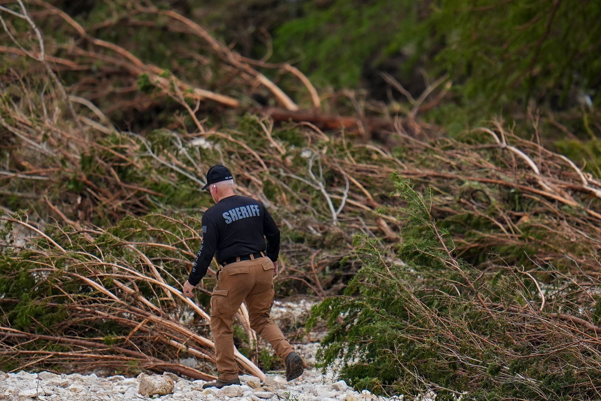 Ein Deputy des Sheriffs durchkämmt die Ufer des Guadalupe River in der Nähe von Camp Mystic, nachdem eine Sturzflut in Hunt, Texas, das Gebiet überschwemmt hatte.