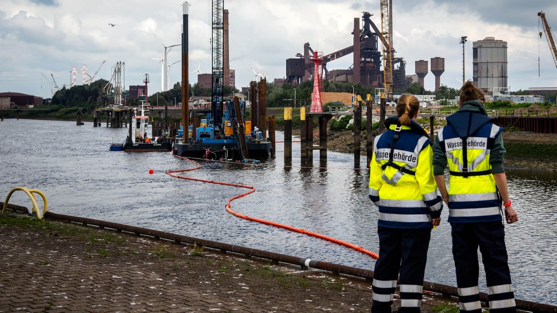 Der gesunkene Schlepper ragt aus dem Wasser: Einsatzkräfte haben eine Ölsperre errichtet.