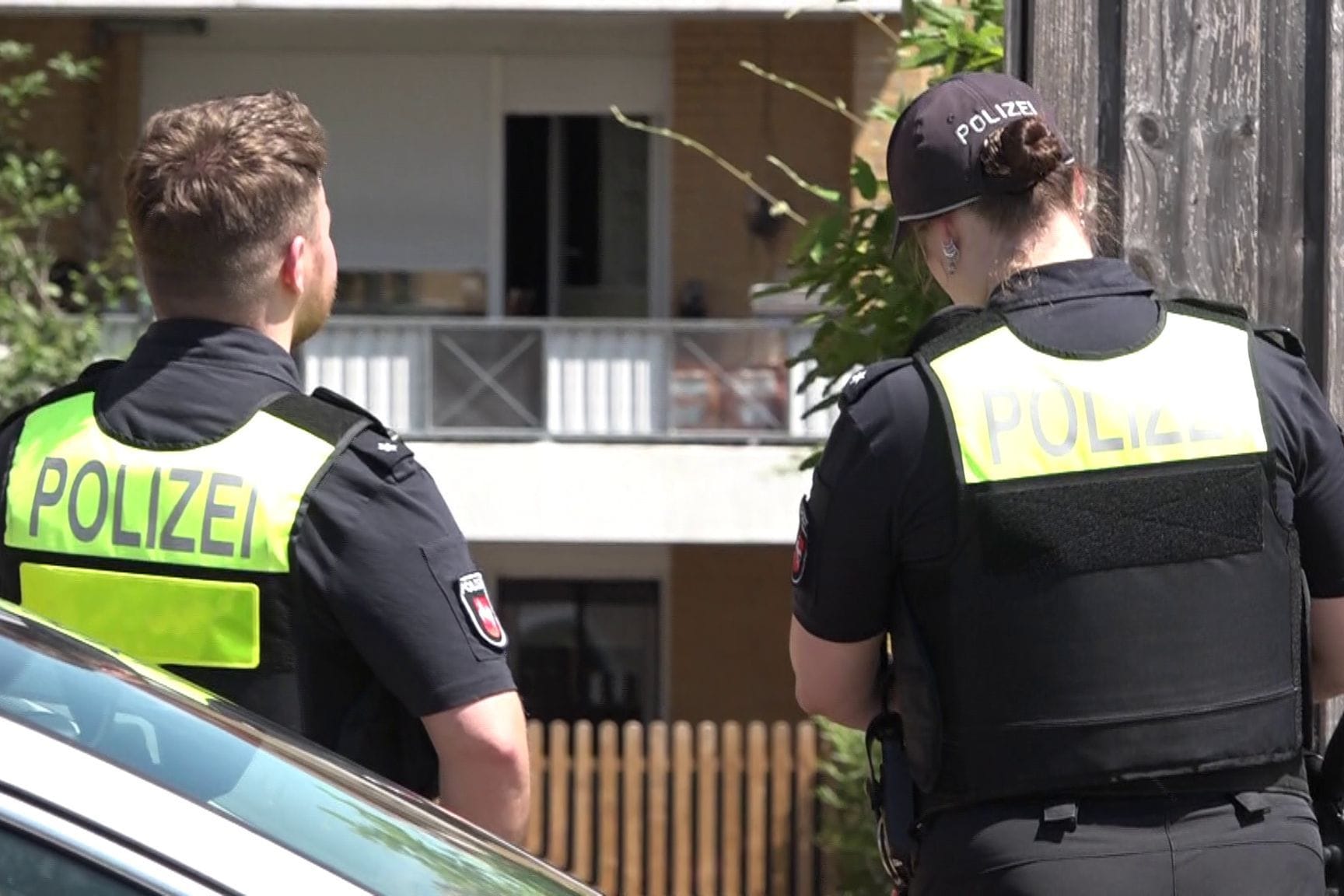 Zwei Polizisten stehen vor einem Mehrfamilienhaus in der Gemeinde Hemmingen. Am Freitagvormittag wird die Polizei hier zu einem Tatort gerufen.
