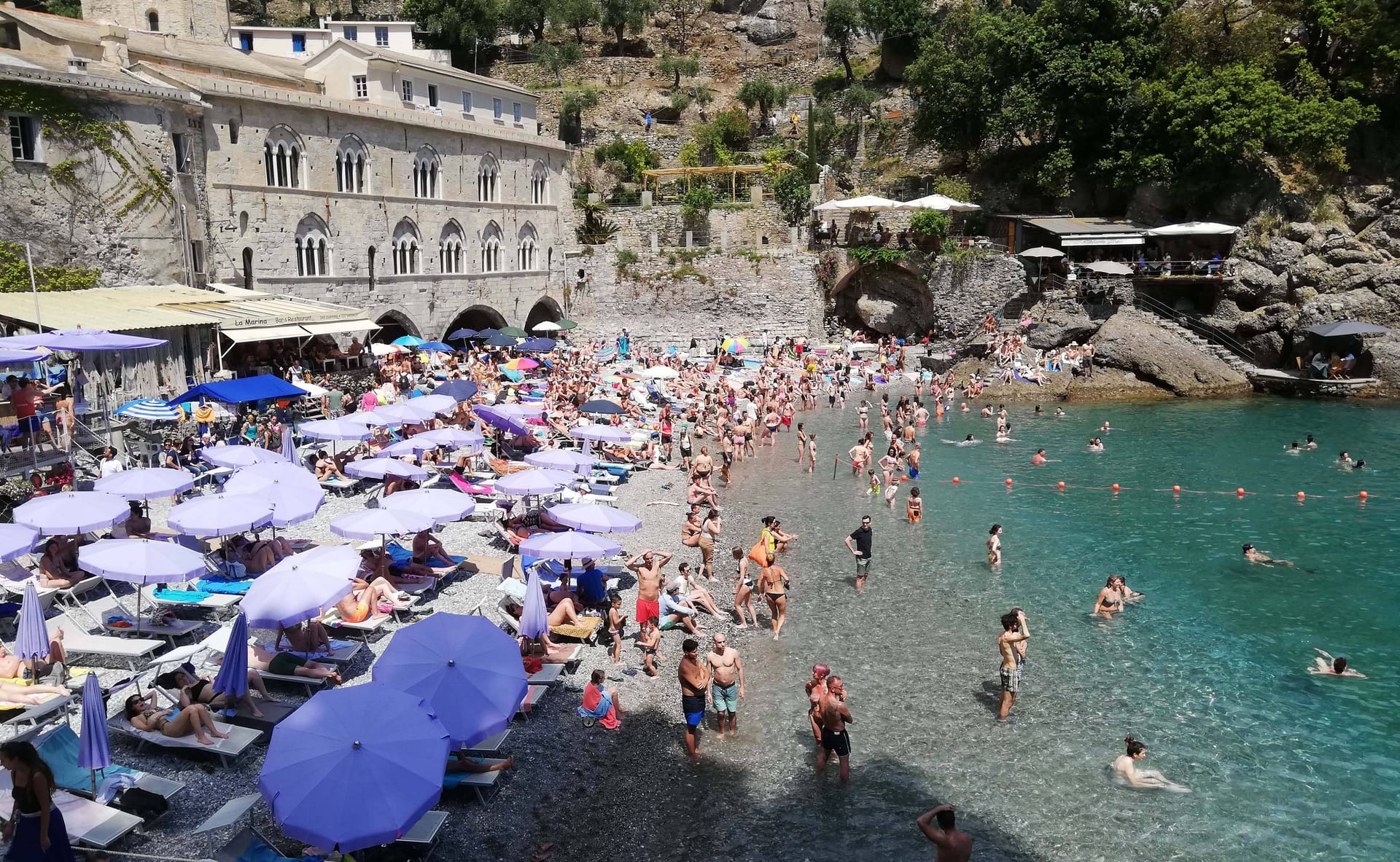 Touristen aalen sich am Strand von San Fruttuoso (Genua) in der Sonne.