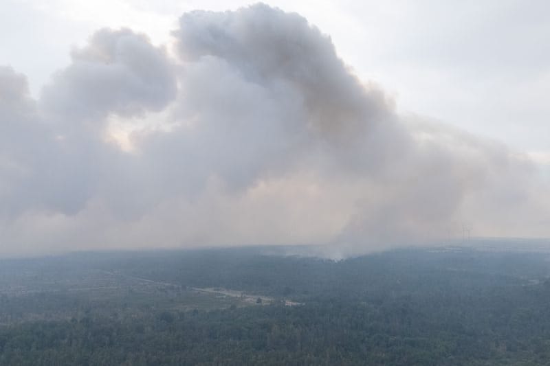 Bei dem Waldbrand in der Gohrischheide erkundet ein Hubschrauber die Brandfläche.