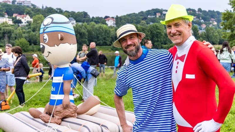 Steve und Kay aus Zwickau nehmen bunt kostümiert zum fünften Mal am Elbeschwimmen teil und stehen vor Elbi, dem Maskottchen der Veranstaltung.