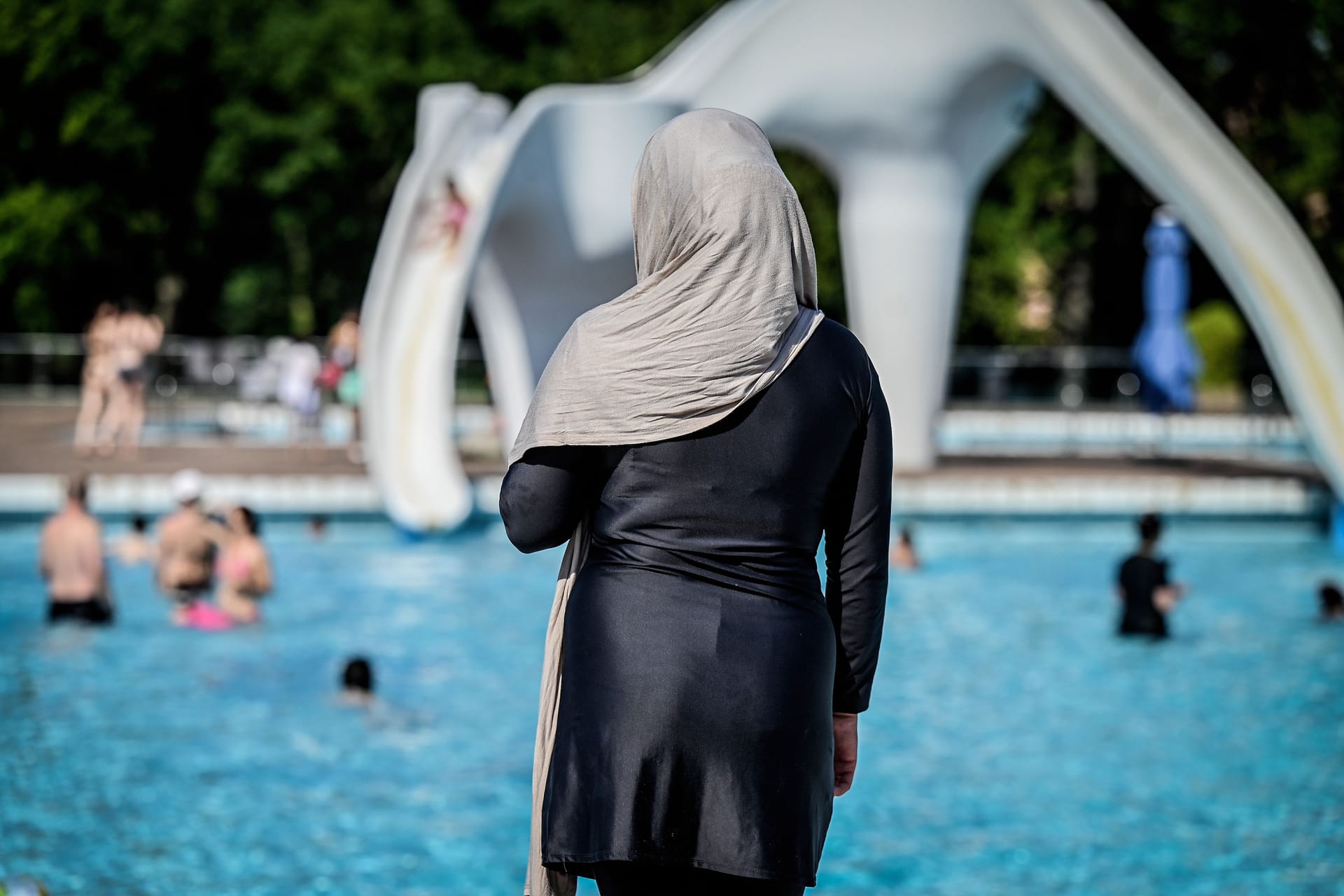 Eine Frau steht im Burkini und Kopftuch in einem Freibad (Archivbild): Im Parkschwimmbad Lörrach ist das verboten.