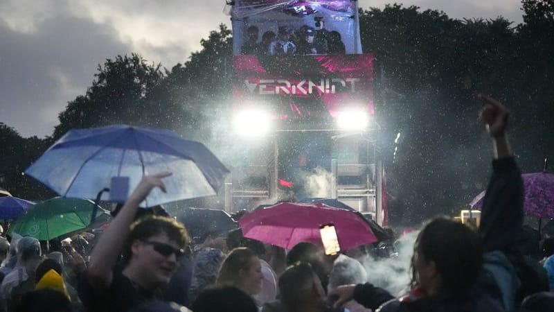 Menschen tanzen trotz starkem Regen in der späten Abenddämmerung bei der Techno-Parade "Rave The Planet". Menschen tanzen trotz starkem Regen in der späten Abenddämmerung bei der Techno-Parade "Rave The Planet".