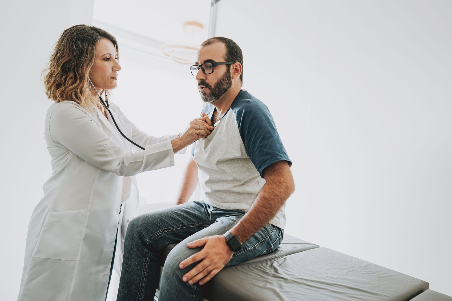 Ärztin hört das Herz eines Patienten ab: Sarkoidose macht sich selten am Herzen bemerkbar.
