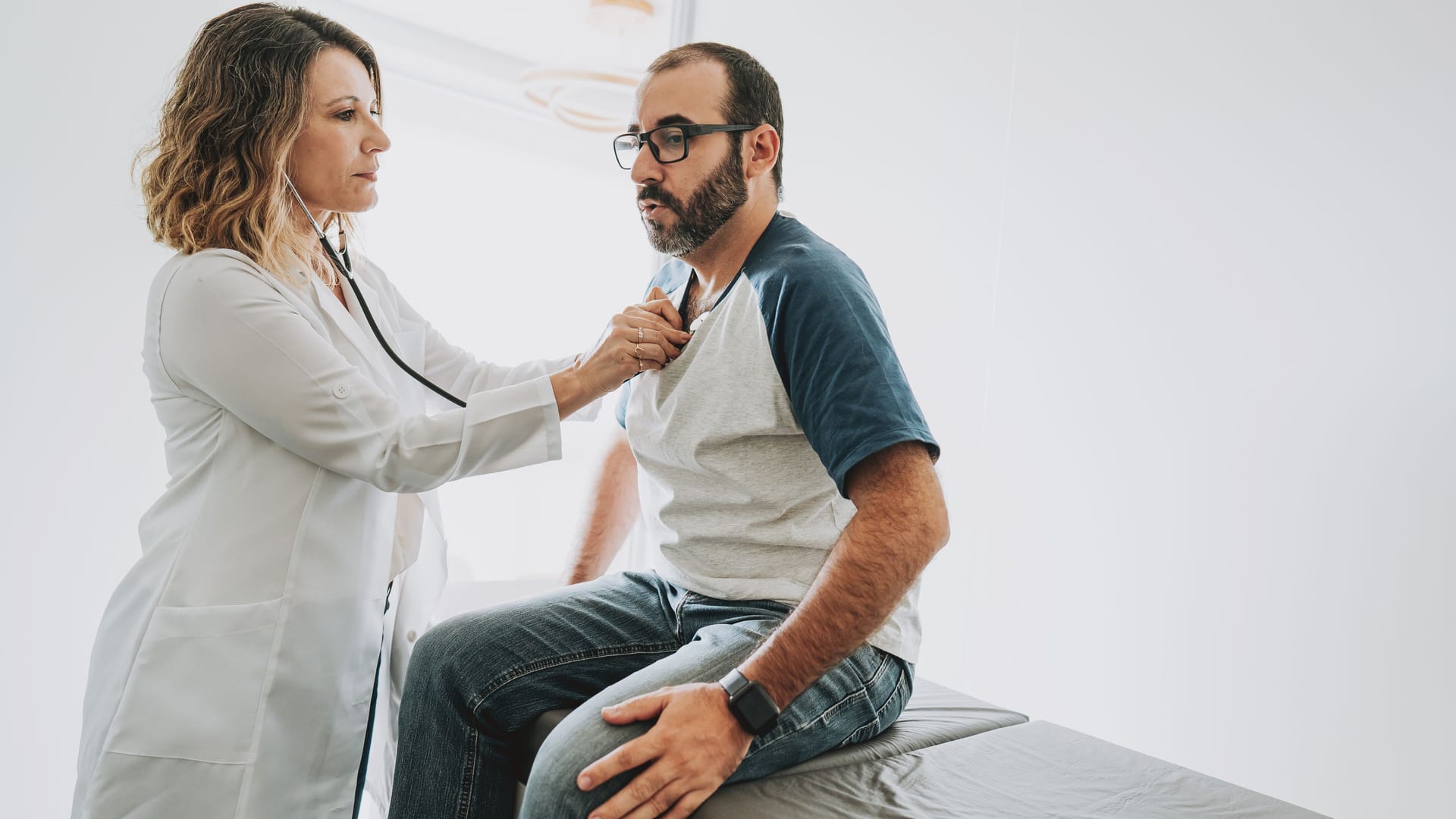 Ärztin hört das Herz eines Patienten ab: Sarkoidose macht sich selten am Herzen bemerkbar. Ärztin hört das Herz eines Patienten ab: Sarkoidose macht sich selten am Herzen bemerkbar.
