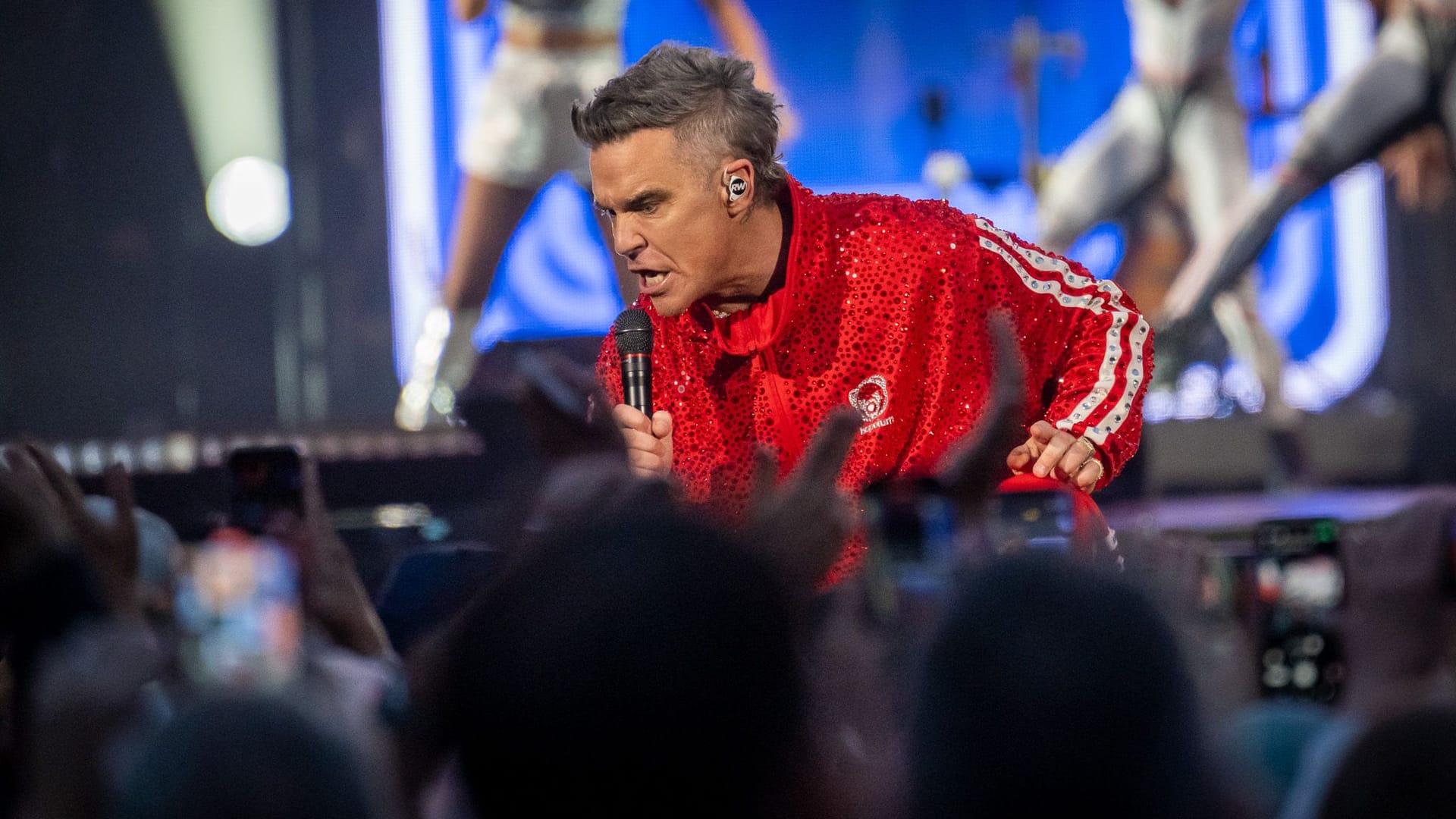 Robbie Williams sucht die Nähe zu seinen Fans im Olympiastadion München: Im knallroten Glitzer-Trainingsanzug.