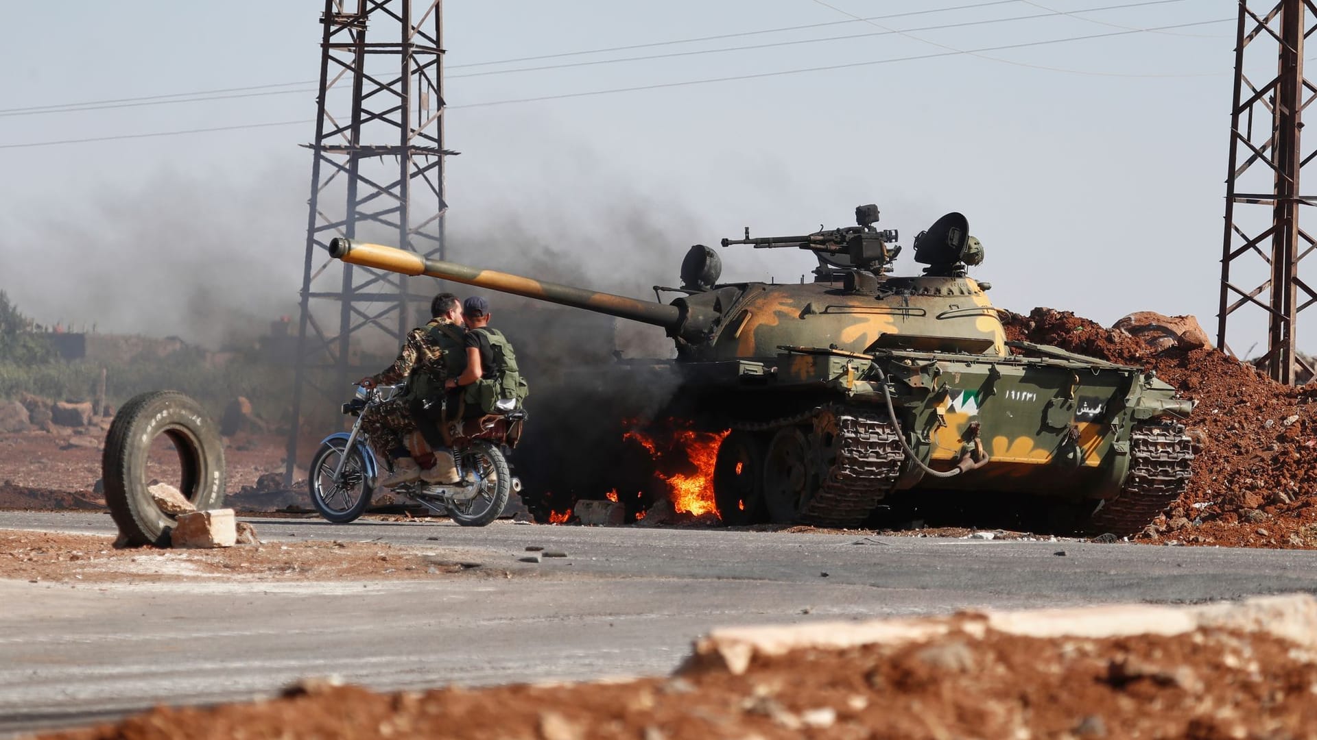 Busra al-Harir: Syrische Regierungssoldaten fahren auf einem Motorrad an einem brennenden Panzer am Stadtrand von Sweida vorbei, wo es zu Zusammenstößen zwischen drusischen Milizen und sunnitischen Beduinenclans gekommen ist.