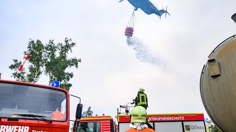 Ein Löschhubschrauber der Bundeswehr und Kräfte der Feuerwehr sind im Waldbrand in der Gohrischheide im Einsatz. Ein Löschhubschrauber der Bundeswehr und Kräfte der Feuerwehr sind im Waldbrand in der Gohrischheide im Einsatz.