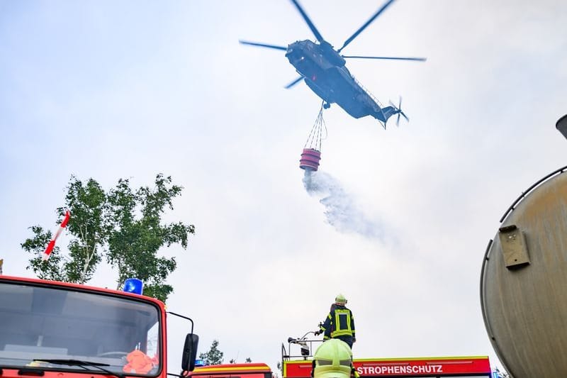 Ein Löschhubschrauber der Bundeswehr und Kräfte der Feuerwehr sind im Waldbrand in der Gohrischheide im Einsatz.