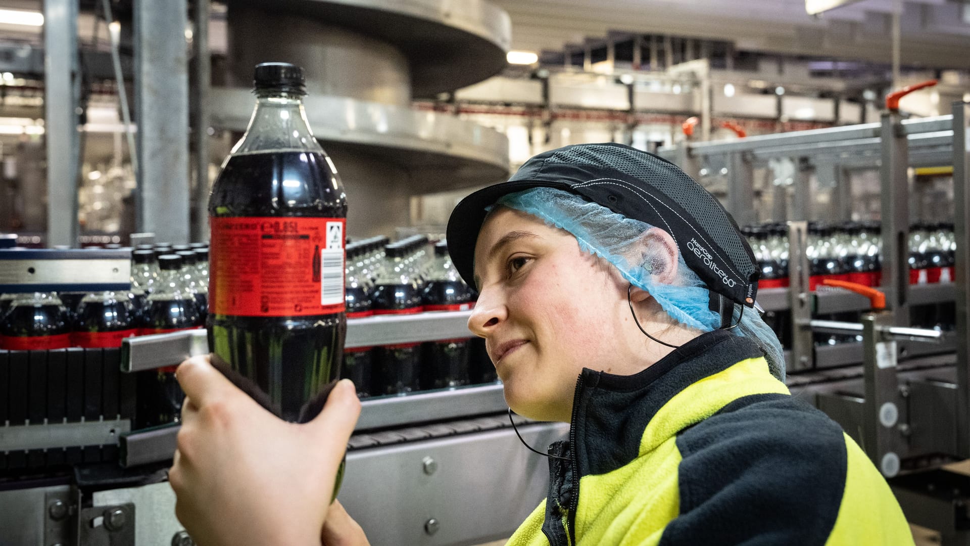 Eine Frau prüft eine Coca-Cola-Flasche (Symbolbild): Die Abfüllanlage befindet sich im nordrhein-westfälischen Dorsten.