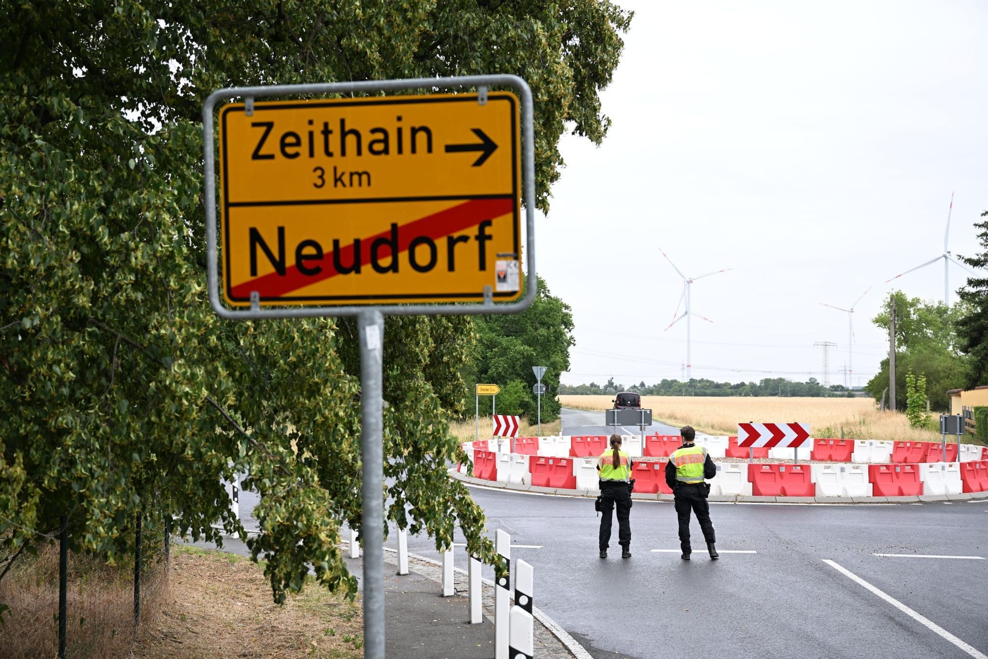Polizisten stehen anlässlich einer Evakuierung am Ortseingang hinter einer Ortstafel. Wegen eines Waldbrandes ist für drei Gemeinden im Osten Deutschlands Katastrophenalarm ausgelöst worden.