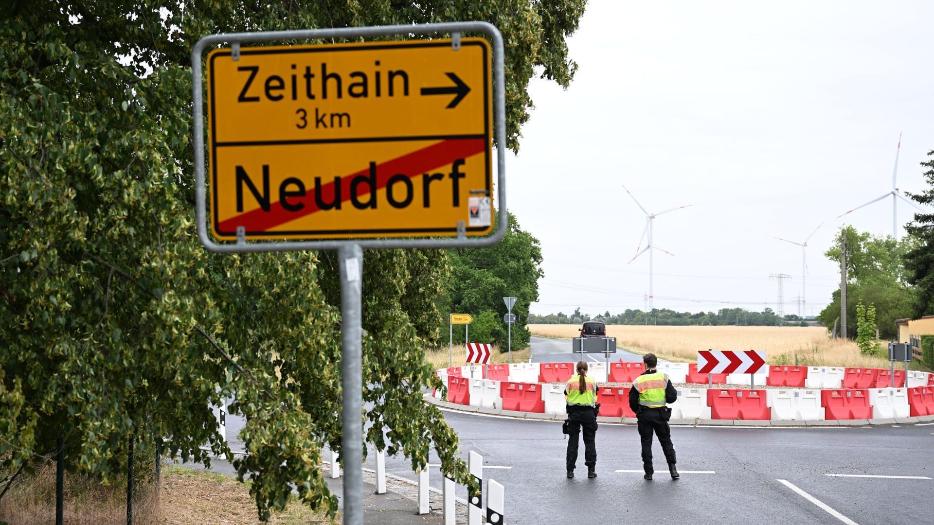 Polizisten stehen anlässlich einer Evakuierung am Ortseingang hinter einer Ortstafel. Wegen eines Waldbrandes ist für drei Gemeinden im Osten Deutschlands Katastrophenalarm ausgelöst worden.