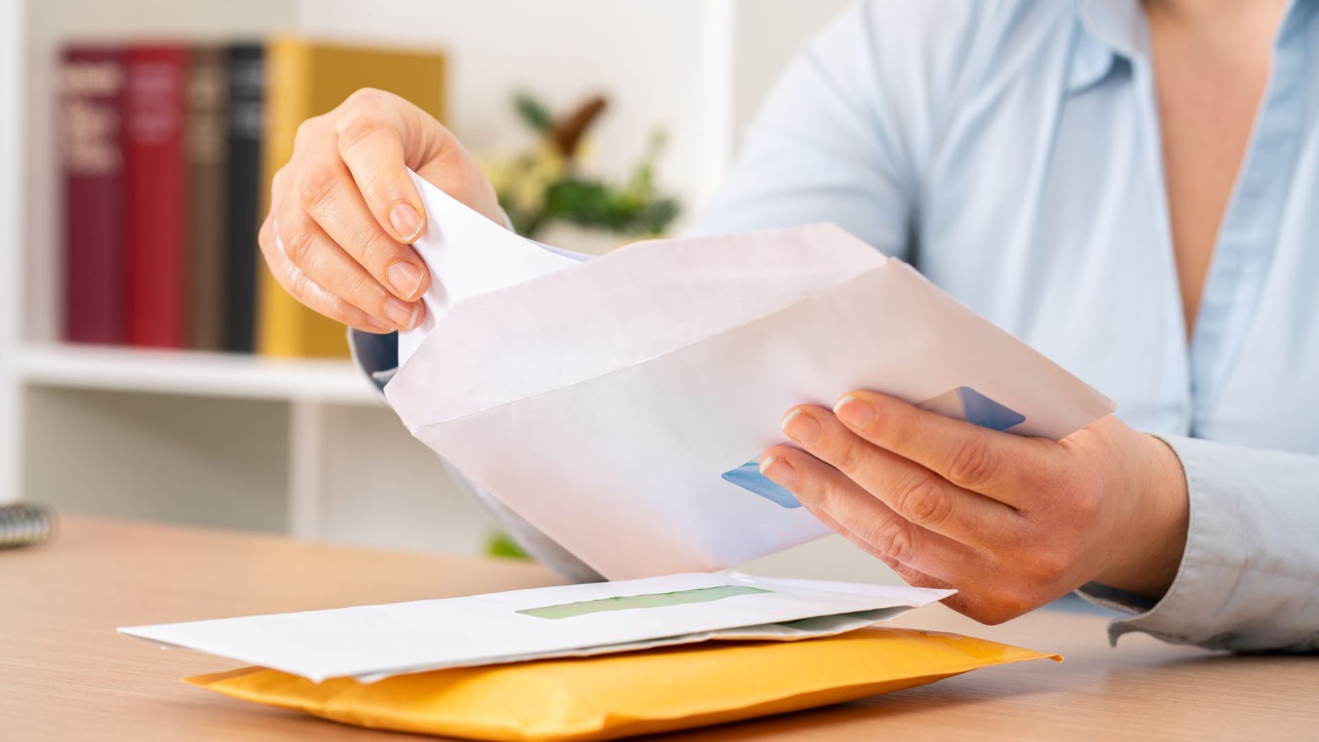 Eine Frau öffnet einen Brief (Symbolbild): Eine Kölnerin erhielt 173 Briefwahlunterlagen.