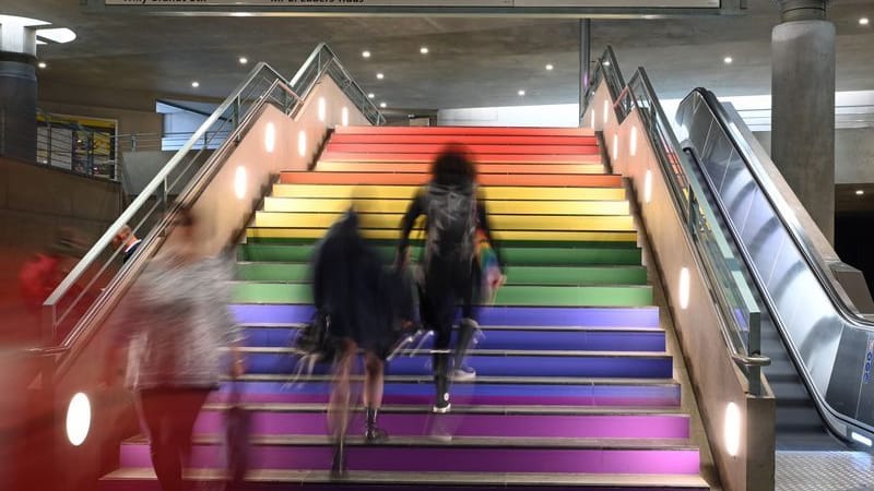 Menschen gehen im U-Bahnhof Bundestag eine in Regenbogen bemalte Treppe hinau: Am Bundestag soll die Regenbogenflagge zum Christopher Street Day diesmal nicht wehen – der U-Bahnhof daneben erstrahlt dagegen in bunten Farben.