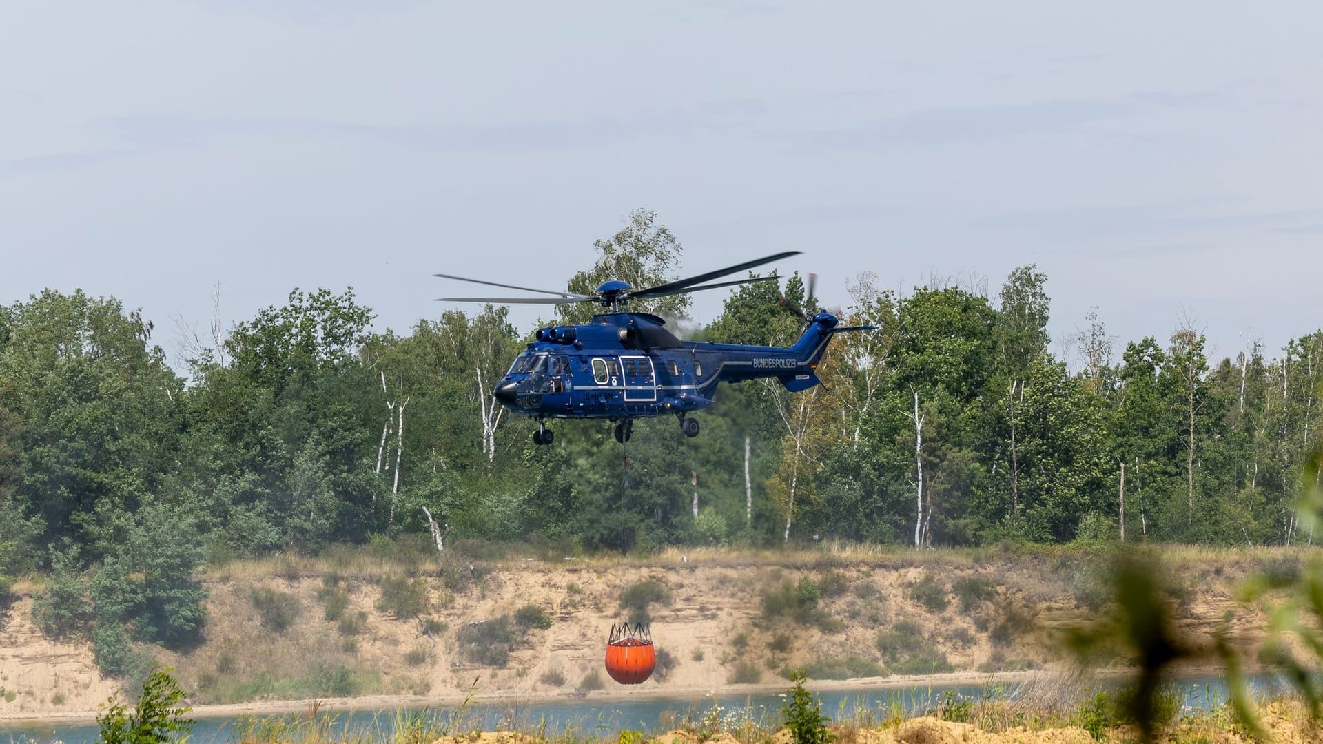 Ein Löschhubschrauber der Bundespolizei nimmt Wasser auf, um den Waldbrand zu bekämpfen.