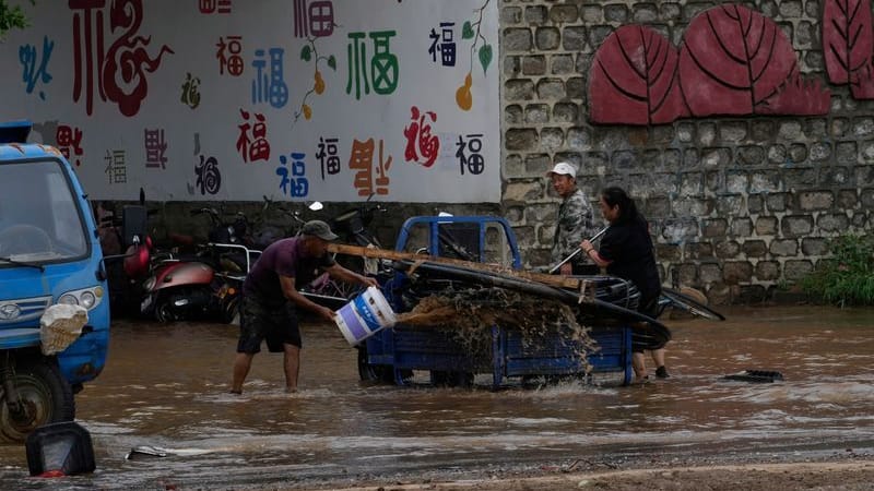 Menschen reinigen ihr Fahrzeug in den Fluten nach starkem Regen im Bezirk Miyun am Stadtrand von Peking.