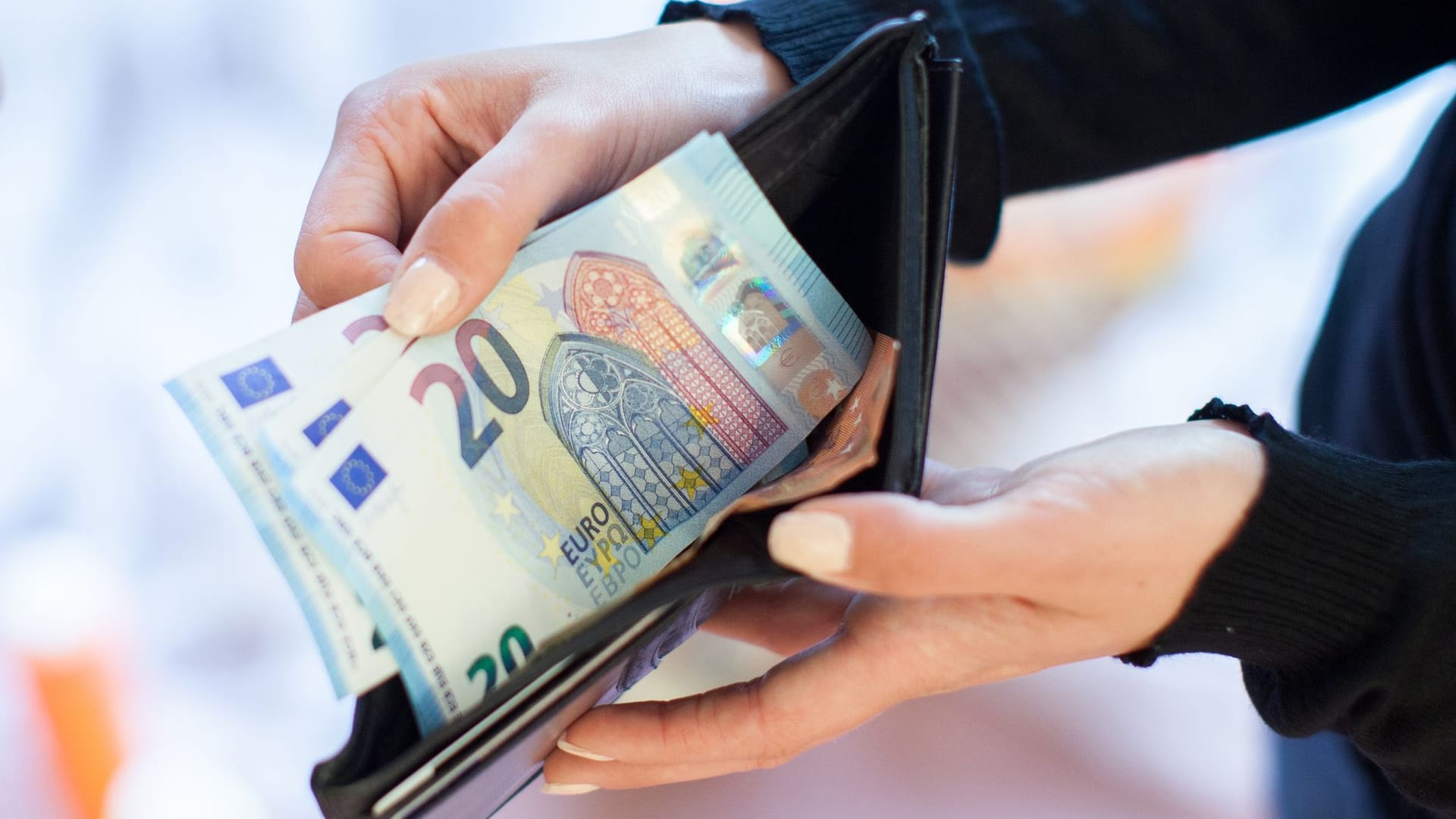 Eine Frau holt Geldscheine aus ihrer Geldbörse