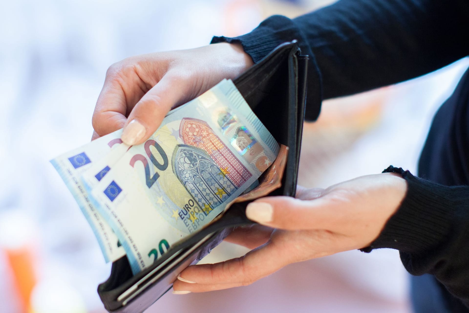 Eine Frau holt Geldscheine aus ihrer Geldbörse