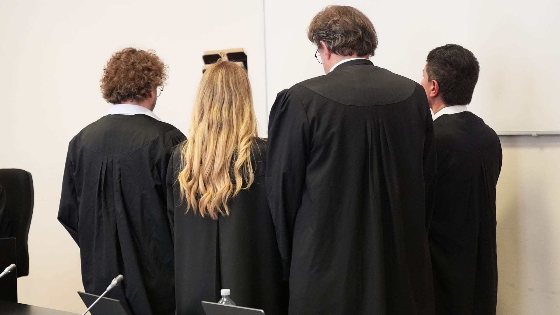 Die drei angeklagten Frauen (nicht zu sehen) stehen hinter ihren Anwälten: Sie sollen ihrem Sohn bzw. Bruder bei der Planung des Mordversuchs geholfen haben. Die drei angeklagten Frauen (nicht zu sehen) stehen hinter ihren Anwälten: Sie sollen ihrem Sohn bzw. Bruder bei der Planung des Mordversuchs geholfen haben.