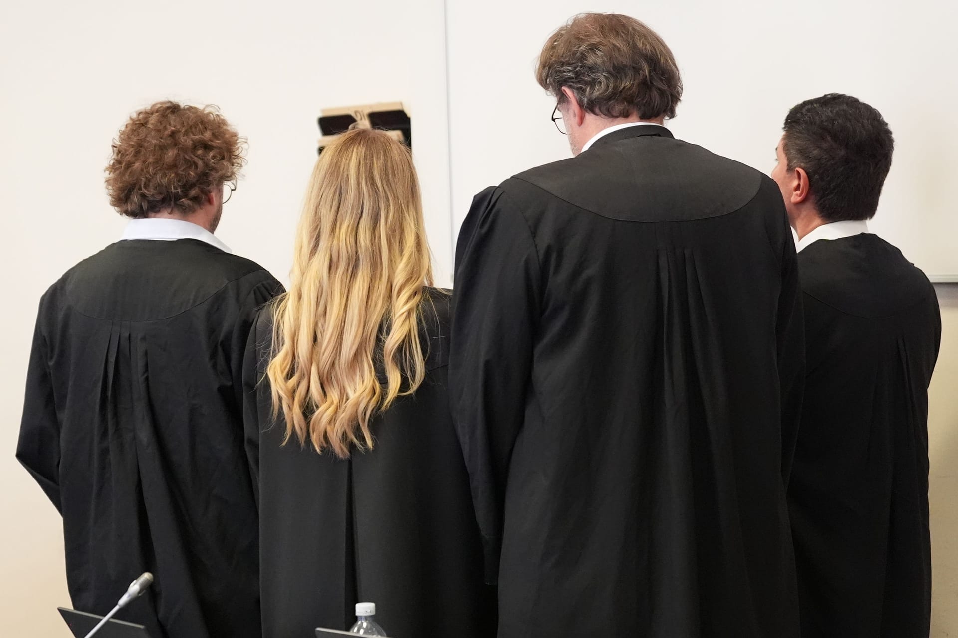 Die drei angeklagten Frauen (nicht zu sehen) stehen hinter ihren Anwälten: Sie sollen ihrem Sohn bzw. Bruder bei der Planung des Mordversuchs geholfen haben.