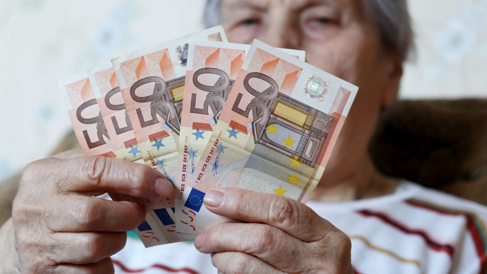 Rentnerin hält Geldscheine: Noch kann man sich die Rente auf Wunsch bar auszahlen lassen.
