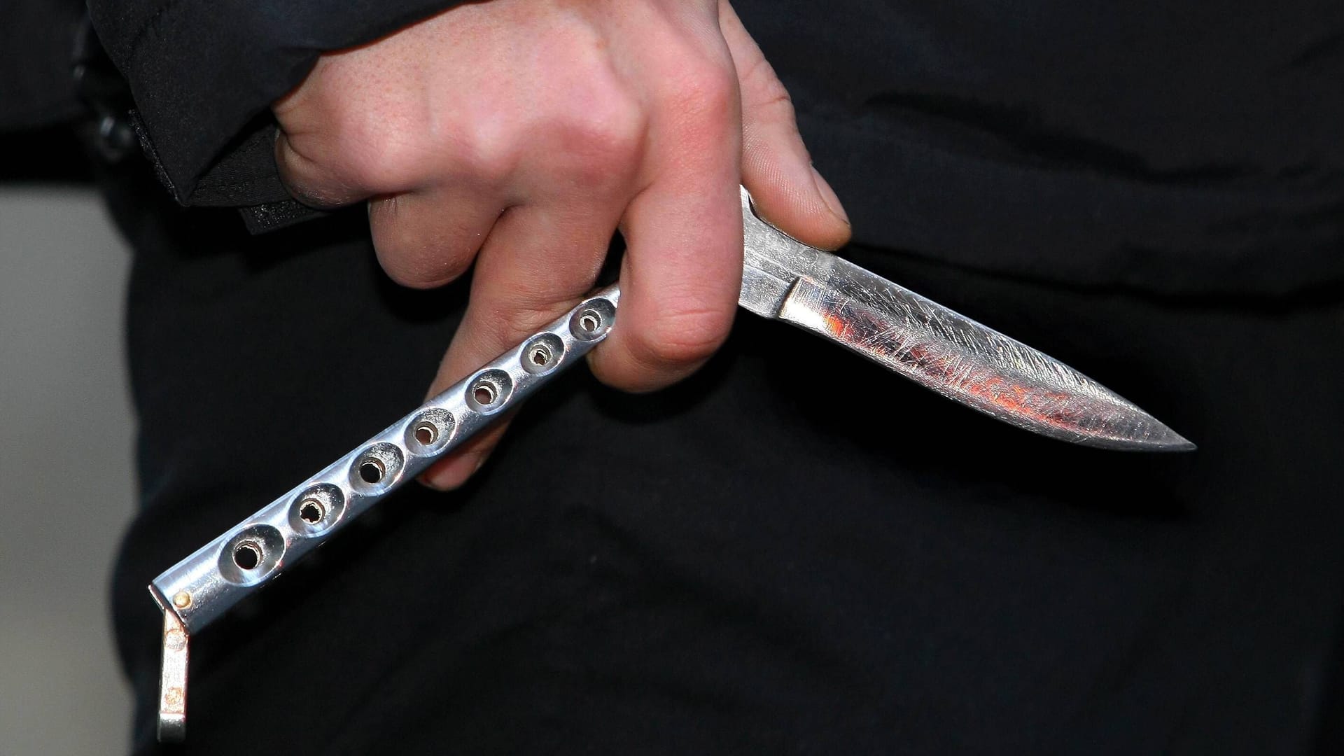Ein junger Mann hält ein Butterflymesser in der Hand (Symbolbild): In Grünwald wurde ein 31-Jähriger bei einem Streit mit einem Messer verletzt.