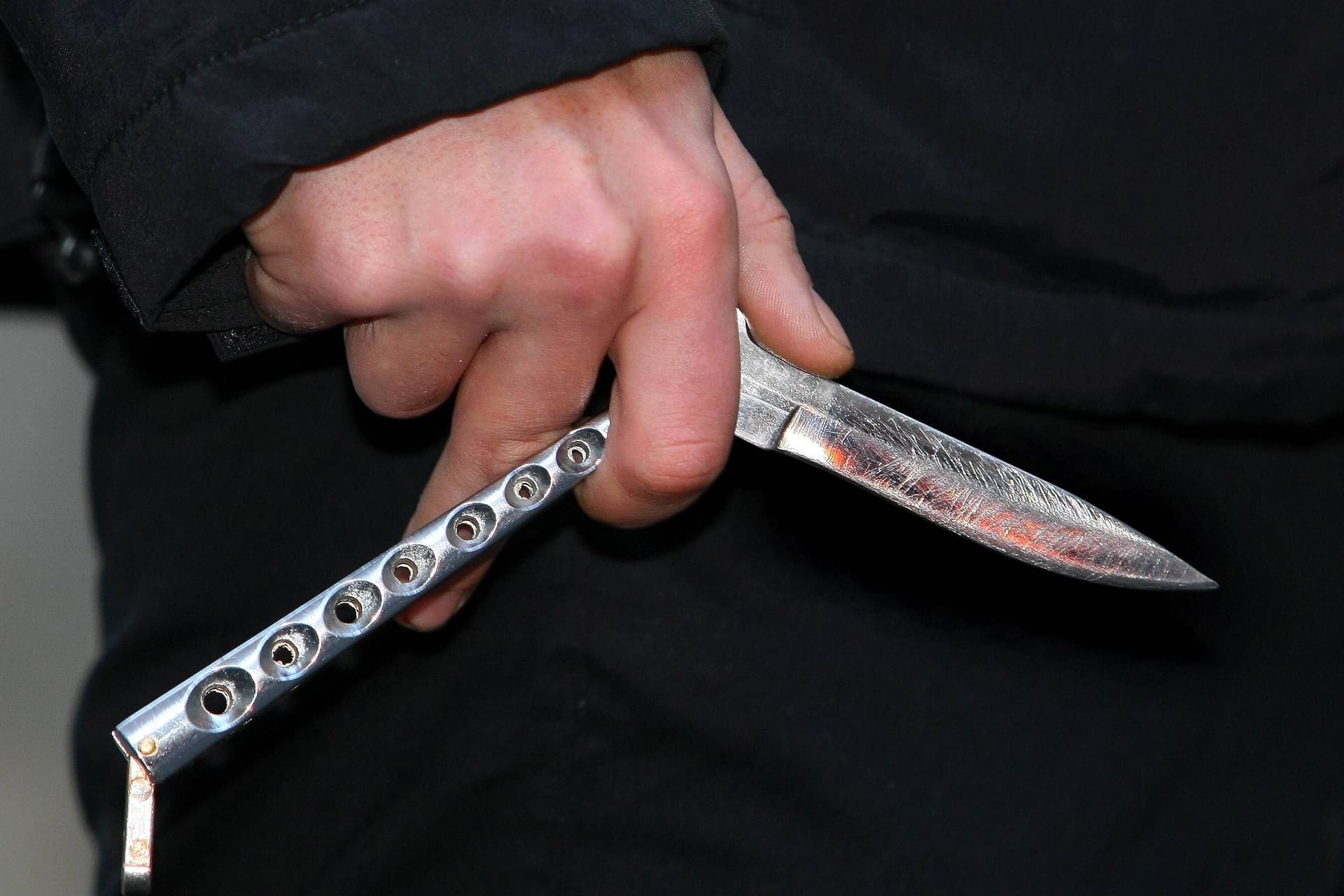Ein junger Mann hält ein Butterflymesser in der Hand (Symbolbild): In Grünwald wurde ein 31-Jähriger bei einem Streit mit einem Messer verletzt.