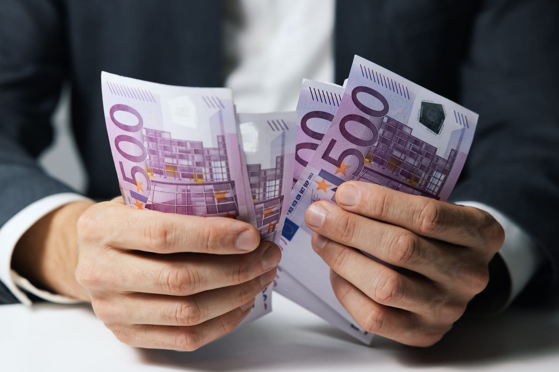 Hände halten mehrere 500-Euro-Geldscheine fest