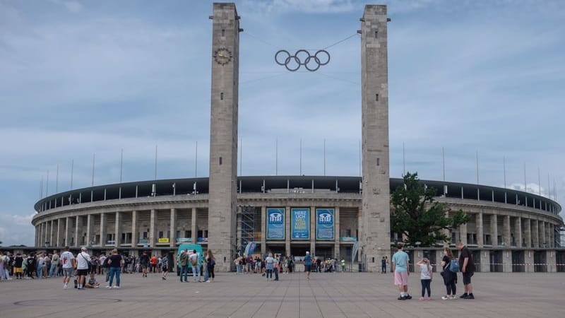Besucher kommen zum Olympiastadion mit dem Olympischen Ringen über dem Eingang.