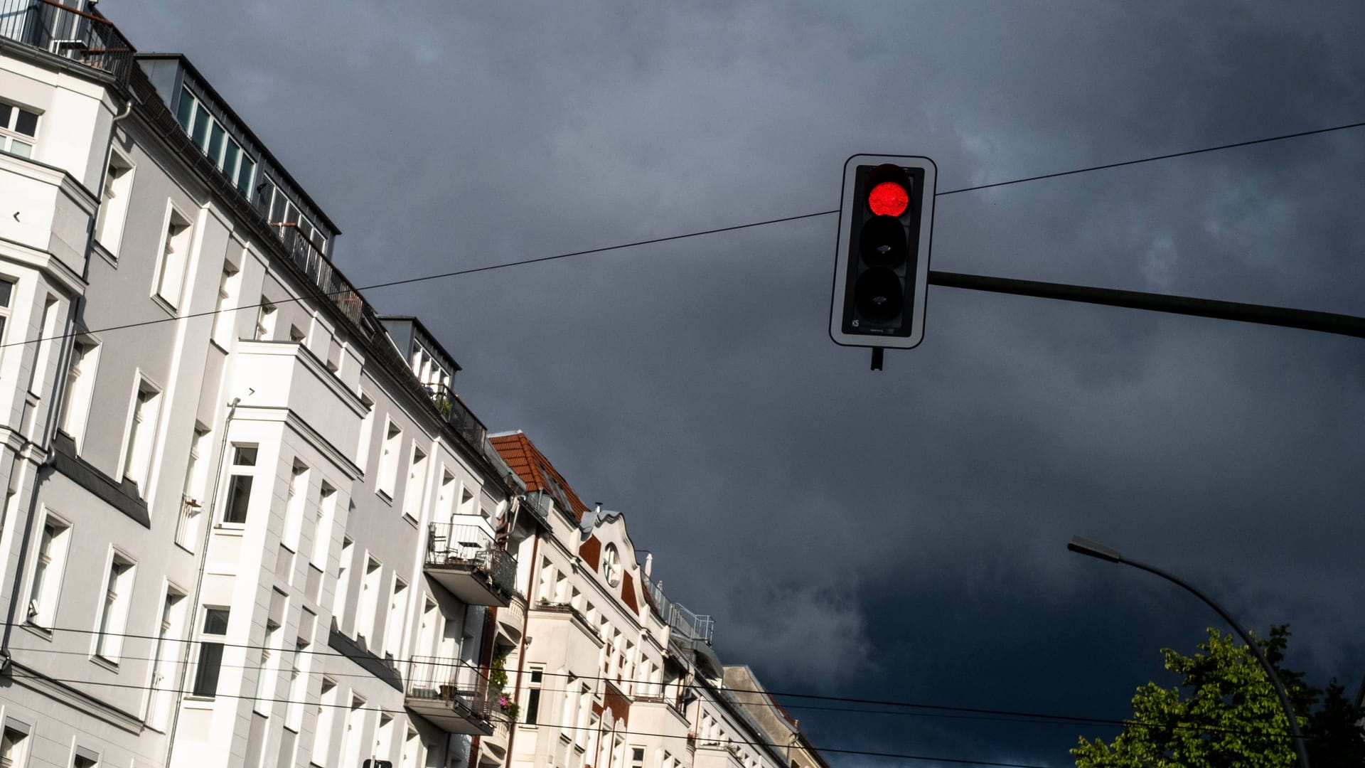 Dunkle Wolken über Häusern (Symbolbild): Die Woche über kann es immer wieder zu Schauern kommen.