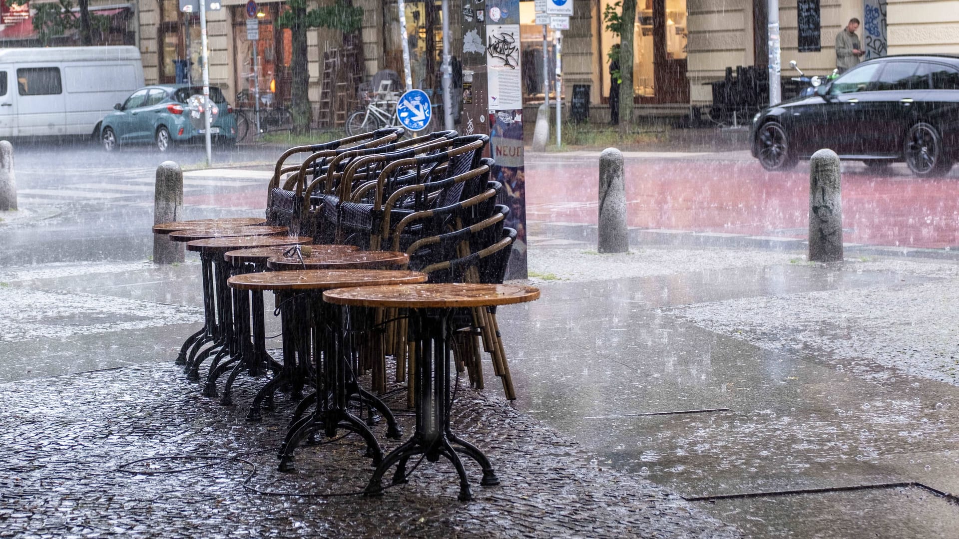 Zusammengestellte Tische und Stühle vor einer Bar in Prenzlauer Berg (Archivbild): Die Feuerwehr musste wegen des Regens ran.