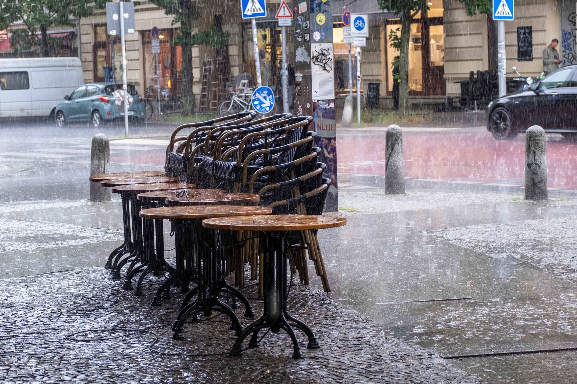 Zusammengestellte Tische und Stühle vor einer Bar in Prenzlauer Berg (Archivbild): Die Feuerwehr musste wegen des Regens ran.