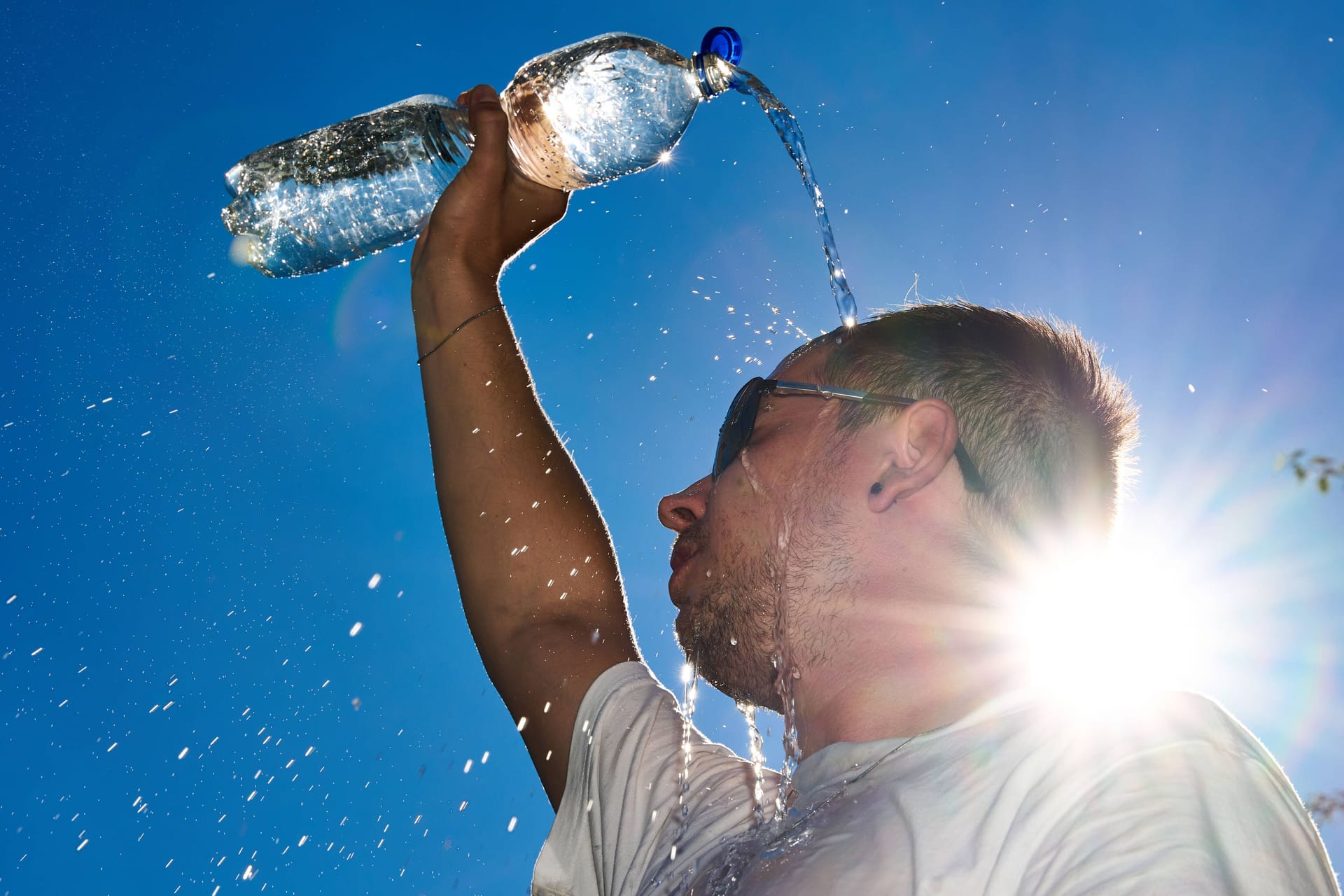 Ein Mann schüttet zur Ablühlung kaltes Wasser über seinen Kopf (Symbolbild): Am Mittwoch können es in Hannover bis 39 Grad warm werden.