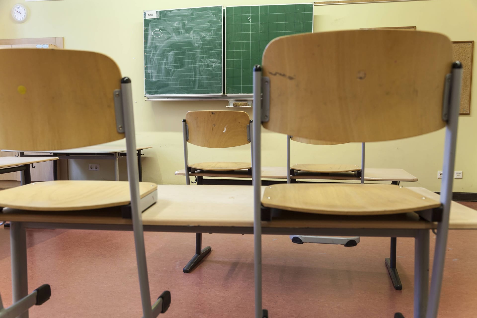 Hochgestellte Stühle in einem Klassenraum (Symbolbild): Bayern will nicht auf seinen späten Ferienstart verzichten.
