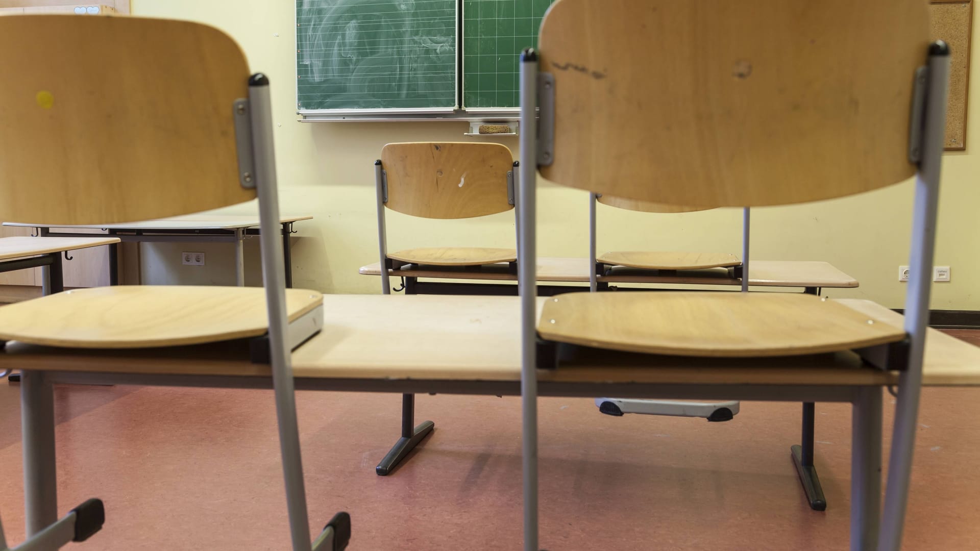 Hochgestellte Stühle in einem Klassenraum (Symbolbild): Bayern will nicht auf seinen späten Ferienstart verzichten.
