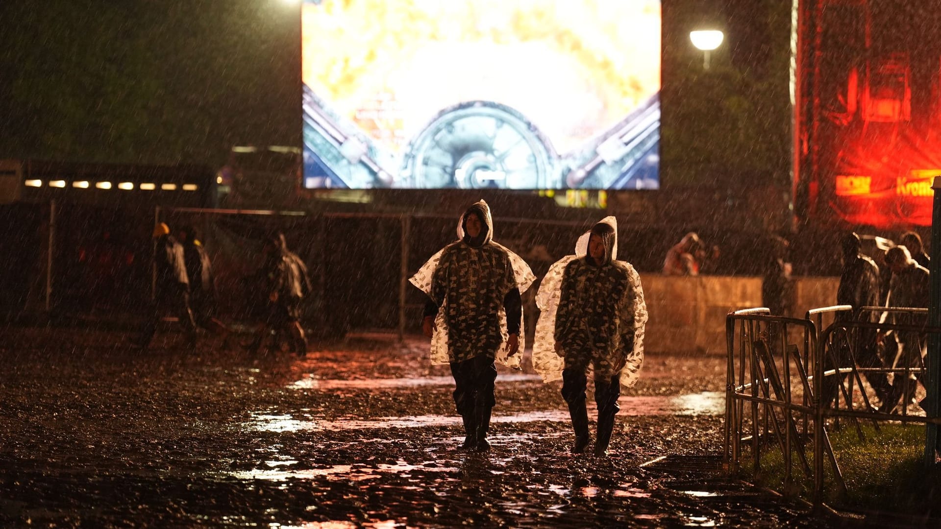 Metal-Fans mit Regenponchos gehen in der Nacht über das Festivalgelände des Wacken Open Air: Der Campingplatz wurde zeitweise geräumt.
