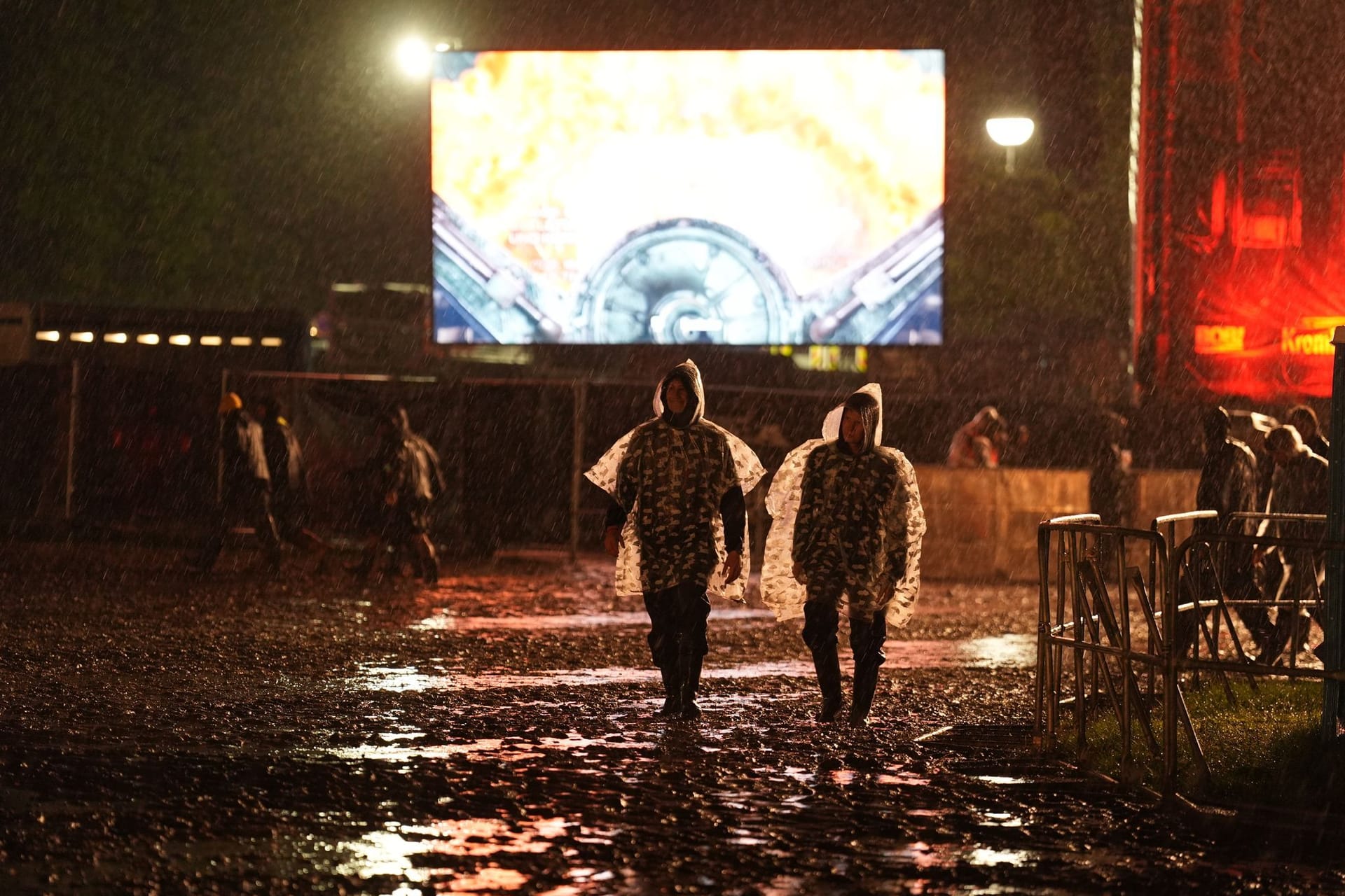 Metal-Fans mit Regenponchos gehen in der Nacht über das Festivalgelände des Wacken Open Air: Der Campingplatz wurde zeitweise geräumt.