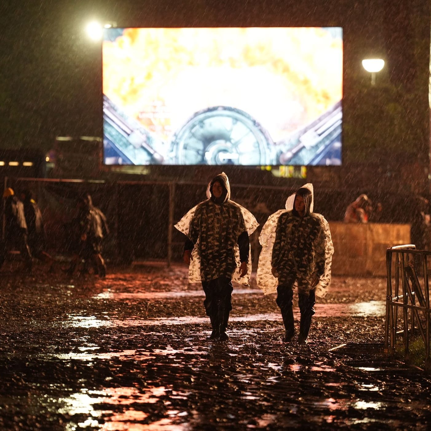 Metal-Fans mit Regenponchos gehen in der Nacht über das Festivalgelände des Wacken Open Air: Der Campingplatz wurde zeitweise geräumt.
