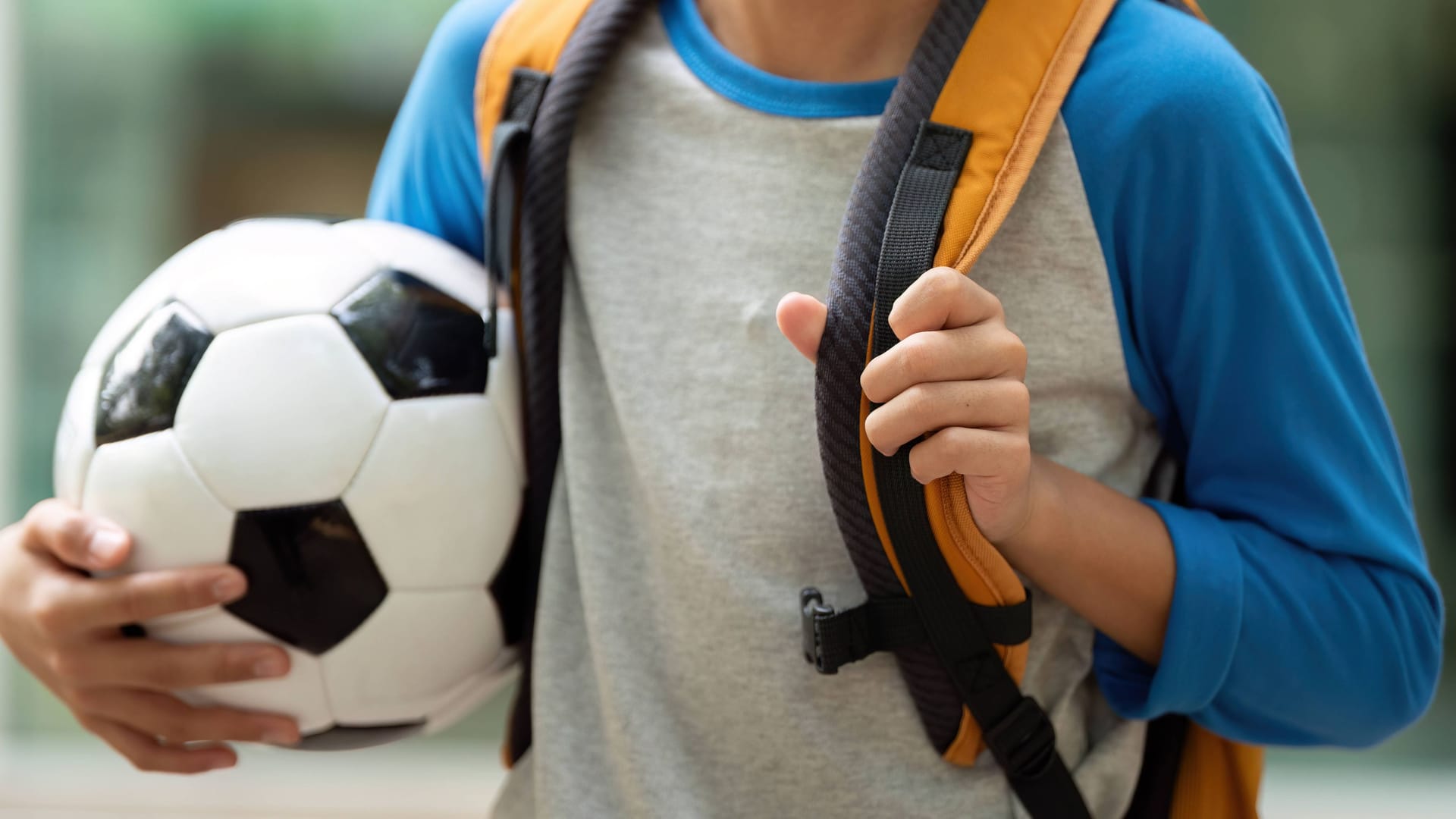 Ein Junge hält einen Fußball (Symbolbild). Beim Versuch, den Ball von einem Hallendach zu holen, kam es zum Unglück.