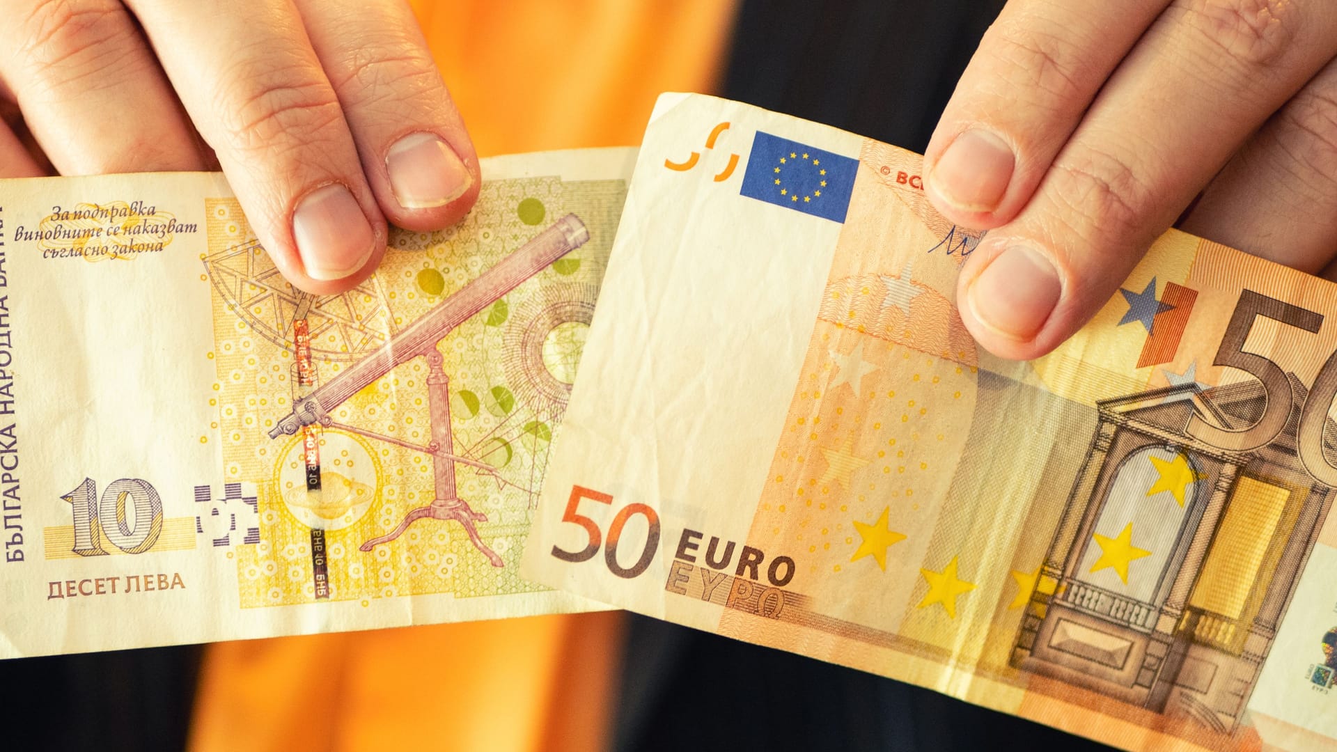 Ein Mann hält einen 10-Lewa-Schein (l.) und eine 50-Euro-Münze in die Kamera: Die Bulgaren sollen ab 2026 zur Euro-Zone gehören.