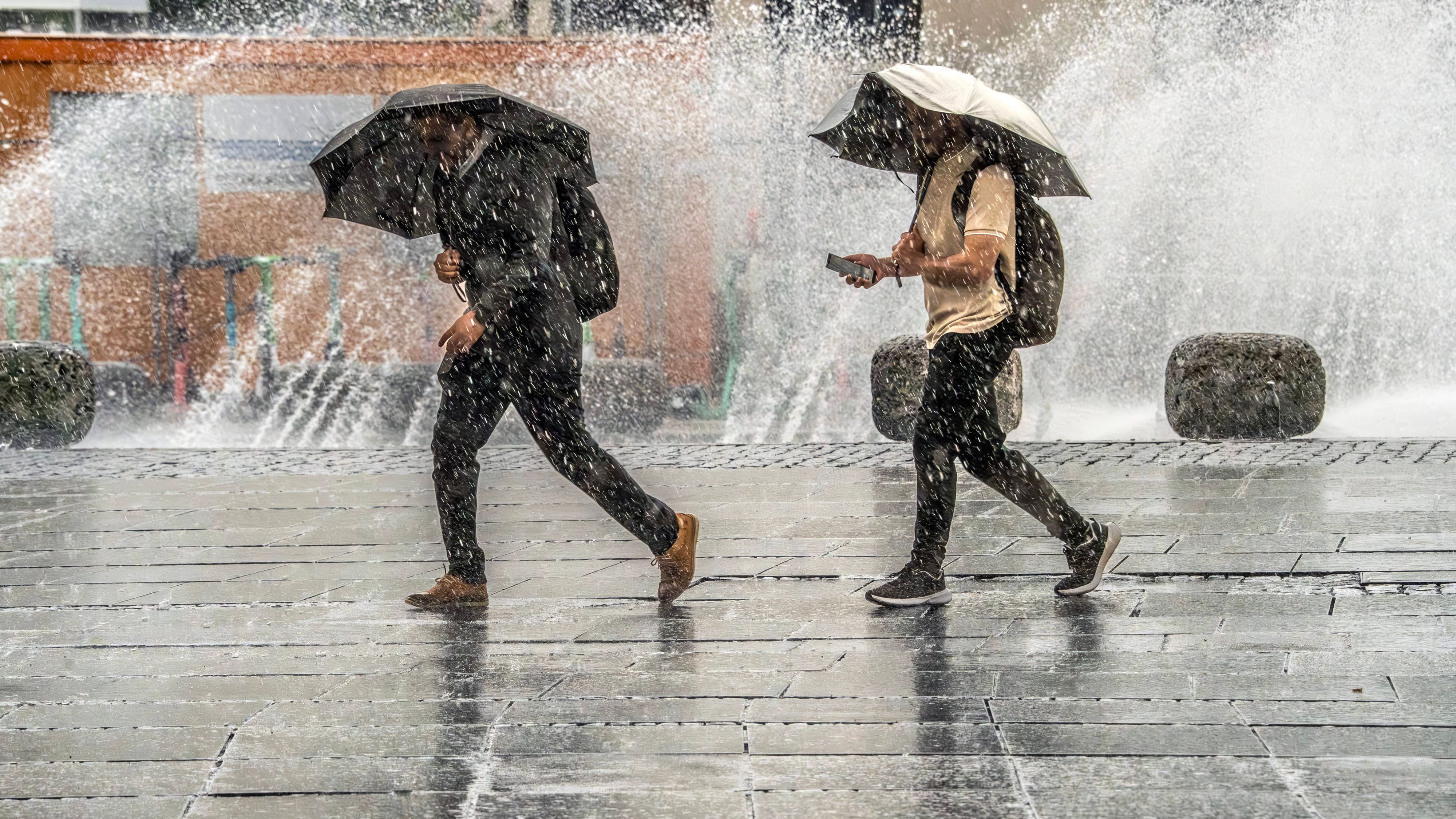 Zwei Menschen in München flüchten vor Starkregen (Archivbild): Das Wetter in Deutschland wird in den kommenden Tagen nass.