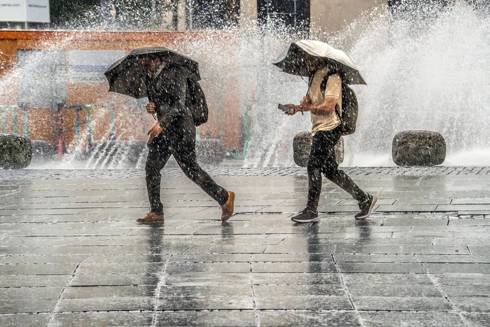 Zwei Menschen in München flüchten vor Starkregen (Archivbild): Das Wetter in Deutschland wird in den kommenden Tagen nass.