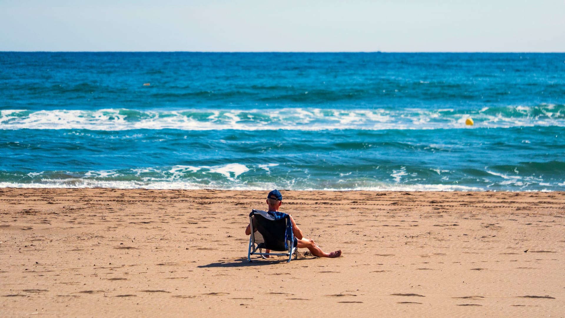 Ein einsamer Tourist am Strand von Roses, Katalonien.