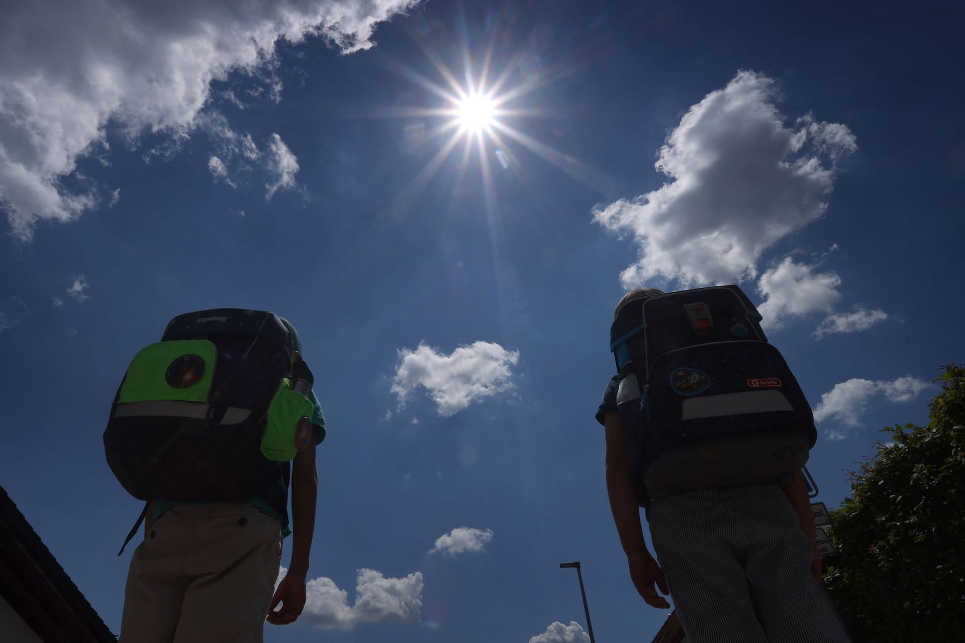 Zwei Schüler mit Ranzen laufen im Sonnenschein