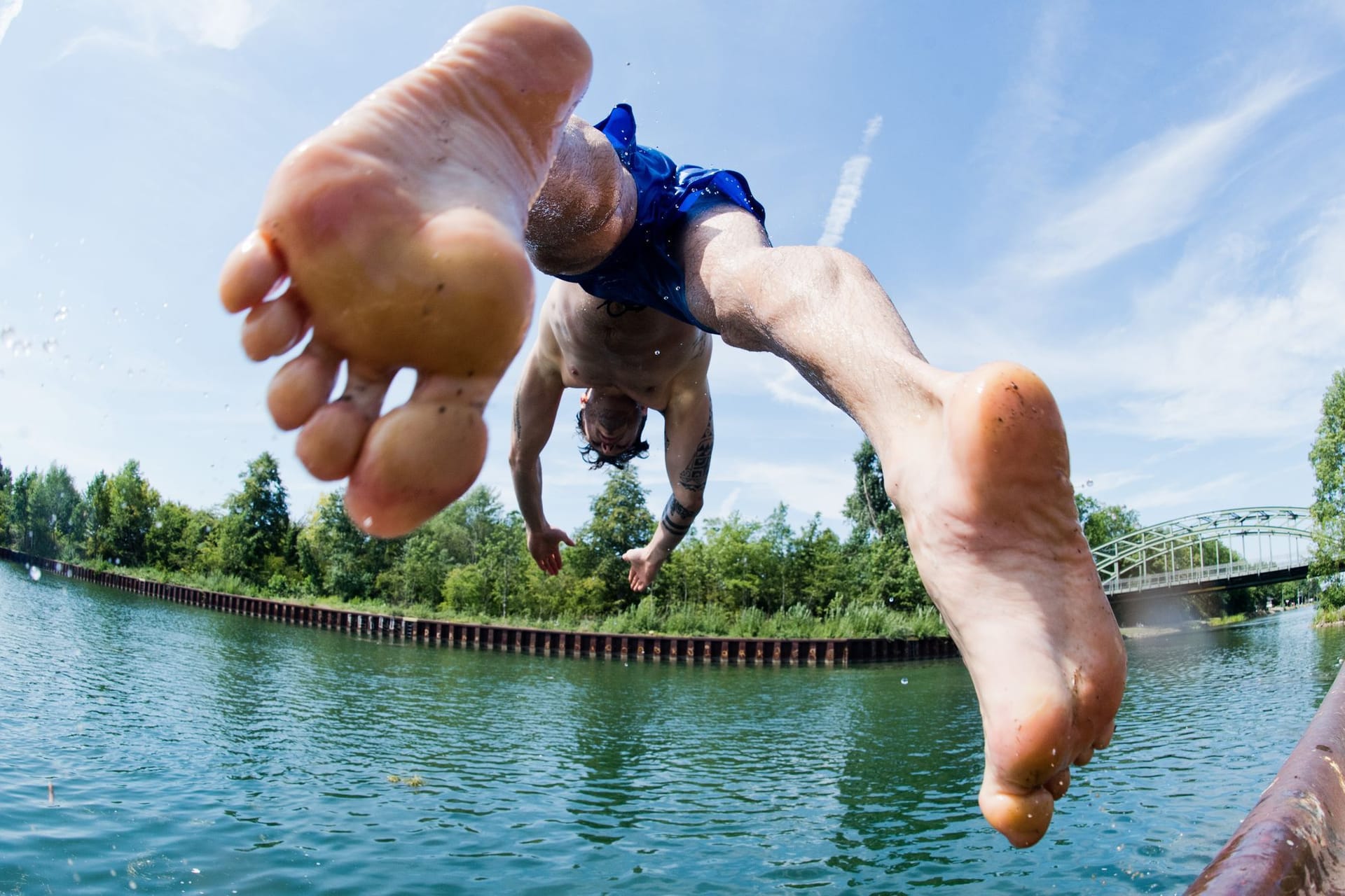 Ein Mann springt ins kühle Nass an einem Kanal