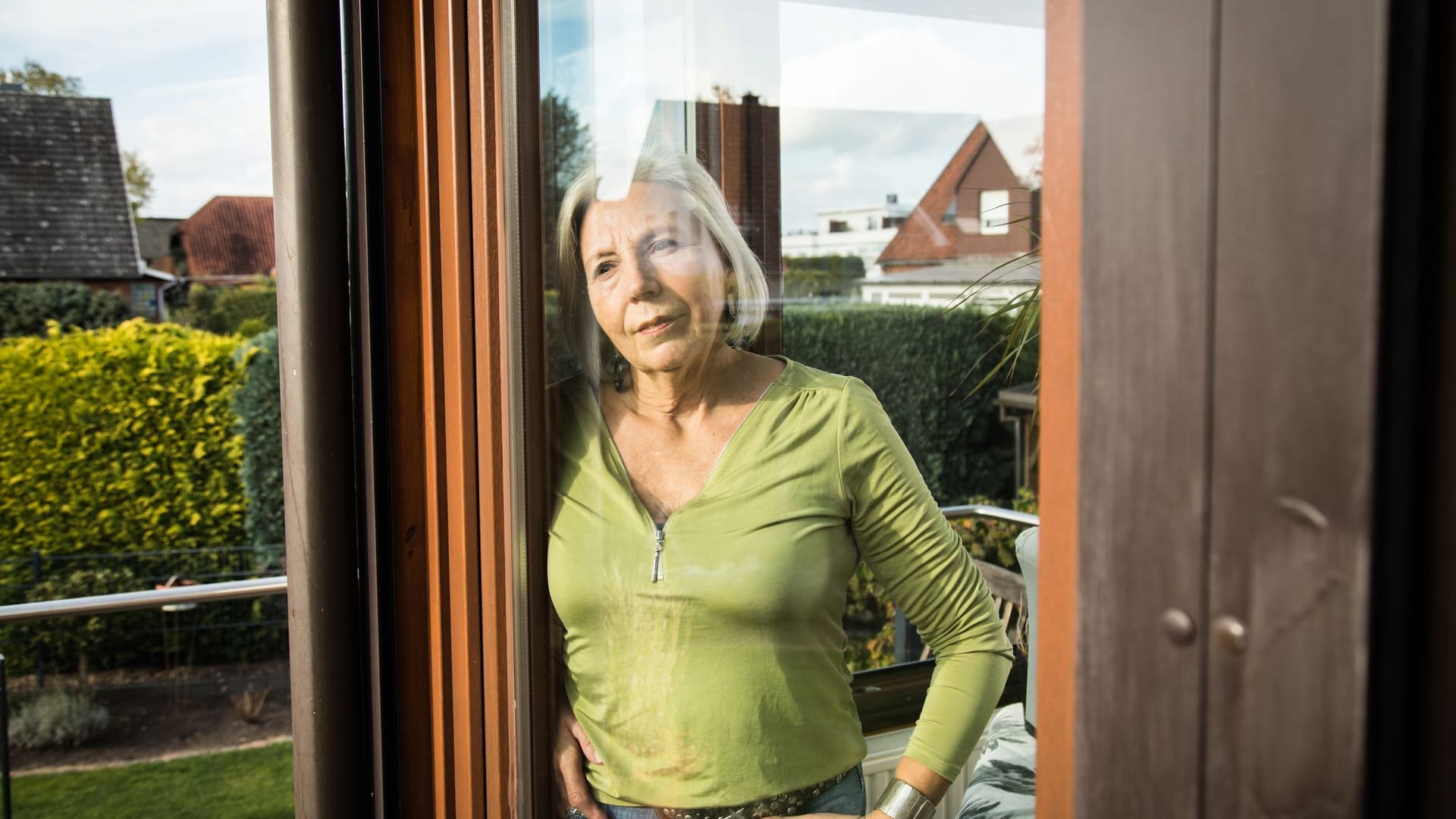 Eine Frau blickt aus einem Fenster auf einen Garten